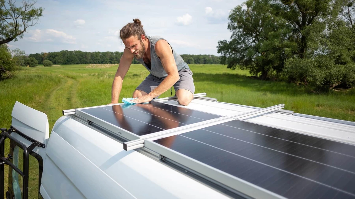 Mann reinigt Solarmodule auf Wohnmobildach